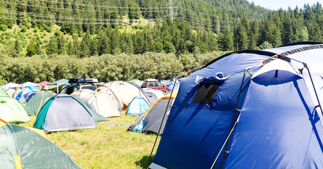 Multiple camping tents pitched in a lush green mountain valley — inflatable camping tent for families